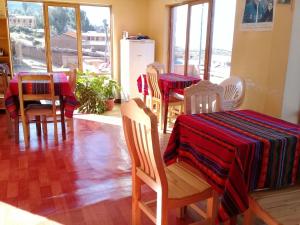 Isla de SolHostal Tawri的一间用餐室,配有两把桌椅和红黑桌布