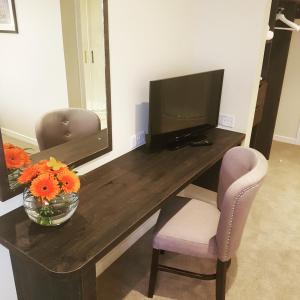 邓甘嫩科汉诺旅馆的一张桌子,带有一台电视和花瓶