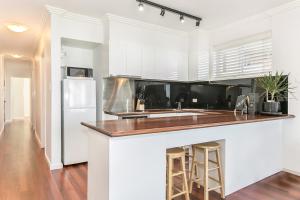 悉尼黄金英里海滨公寓的厨房配有白色橱柜和白色冰箱。
