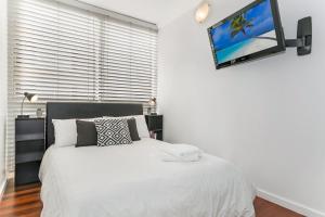 悉尼黄金英里海滨公寓的卧室配有一张床铺,墙上配有电视