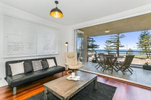 悉尼黄金英里海滨公寓的客厅配有黑色沙发和桌子