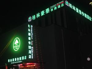 天津格林豪泰天津西青秀川路阳光100的一座晚上有 ⁇ 虹灯标志的建筑