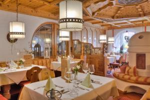 塞尔赖因山谷格里斯Bergsporthotel Antonie的餐厅设有白色的桌椅和吊灯。