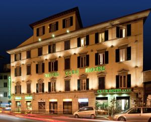 佛罗伦萨c-俱乐部酒店的一座大型建筑,前面有汽车停放