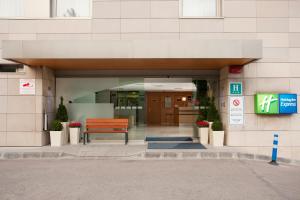 格拉诺列尔斯Holiday Inn Express Barcelona - Montmeló, an IHG Hotel的坐在大楼入口处的长凳