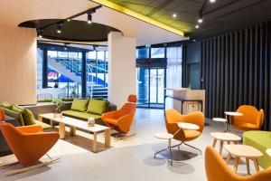 图尔诺富特旅游中心火车站酒店的大堂设有橙色椅子和绿色沙发