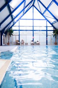 伍德布里奇Ufford Park Resort的大型游泳池设有蓝色天花板和大窗户