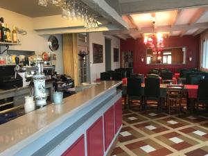 圣皮耶尔代科尔普Hotel Restaurant l'Avenir的一间带酒吧的餐厅以及一间带椅子的用餐室