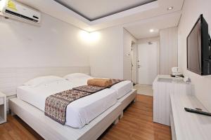 登巴萨彭多克奈曼15号旅馆的白色卧室设有一张大床和电视。