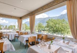 因特拉肯瑞士品质都市酒店的餐厅设有桌椅和大窗户。