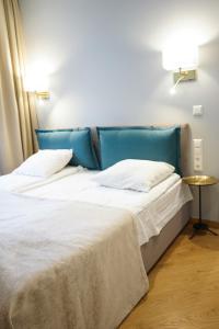 德鲁斯基宁凯塞纳西斯帕斯塔斯旅馆的卧室内的两张床,配有蓝色床头板