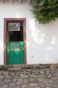 帕拉蒂Casa de Hospedagem Paraty的白色建筑上带标志的绿色门