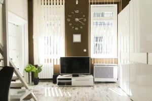 布达佩斯德宾斯基R＆R公寓的客厅配有电视和墙上的时钟