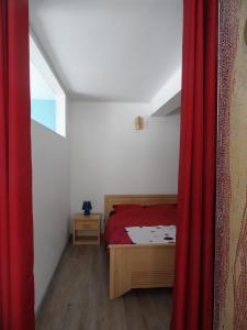 拉旺泽诺Gîte du héron的一间卧室配有床和红色窗帘