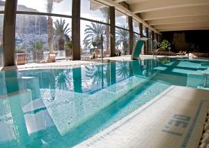 塔乌里托Hotel LIVVO Costa Taurito & Aquapark的大楼内的一个蓝色海水游泳池