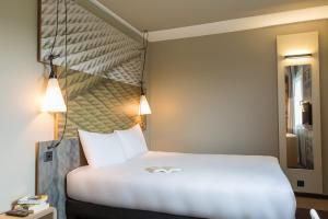 日内瓦日内瓦机场酒店的卧室配有白色的床和床头板