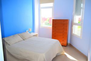 罗塔Apartamento Costa Ballena con WIFI的一间蓝色和白色的卧室,配有一张床和一个梳妆台