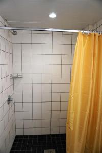 塔尔图市区旅舍的浴室内设有带黄色淋浴帘的淋浴