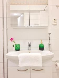 拉赫蒂Lahti Center Design Apartment Uno的浴室设有白色水槽和2个绿色花瓶