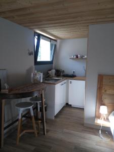 杜萨尔Le chalet du Lac的厨房配有白色橱柜、桌子和窗户。
