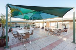 本迪戈贝斯特韦斯特水晶酒店的一个带桌椅和绿色遮阳伞的庭院
