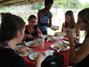 帕西库达Pasikudah Eco Village Hotel的一群坐在桌子旁吃食物的人