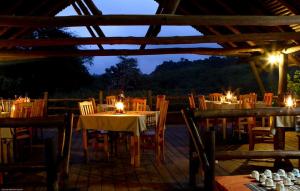 LobambaMlilwane Game Sanctuary的餐厅配有桌椅和灯光