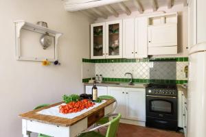 圣焦万尼瓦尔达尔诺Il Nido di Margherita的厨房配有白色橱柜和一张带蔬菜的桌子。
