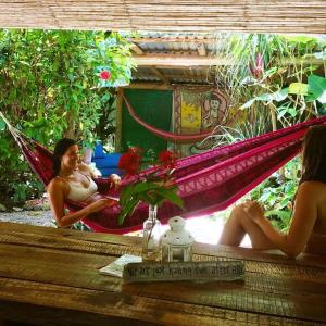 萨玛拉Hostel Mariposas的两名妇女坐在花园里的吊床上