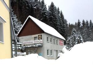 诺伊豪森Wohnen beim Kunsthandwerker的一座被雪覆盖的建筑,有树为背景