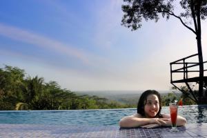 班图尔拉贾克拉纳度假酒店和Spa中心的躺在游泳池里喝一杯的女人