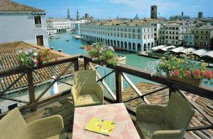 威尼斯佛斯卡里宫殿酒店的阳台配有桌椅,享有运河美景。