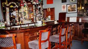 阿德莫尔Round Tower Hotel的酒吧配有木椅和吧台