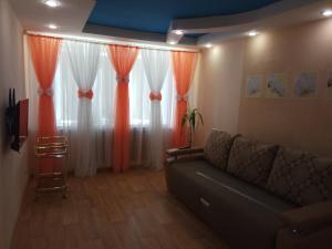 诺里尔斯克Leninskiy Prospekt 25的带沙发和橙色窗帘的客厅