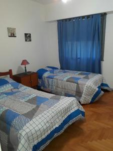 布宜诺斯艾利斯Apartamento Lautaro的配有蓝色窗帘的客房内的两张床