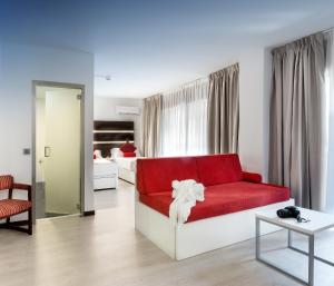 马德里Roisa Hostal Boutique的一间带红色沙发的客厅和一间卧室
