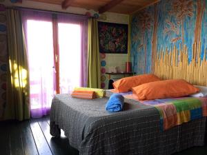 LentellaCasa sull'Albero的一间卧室配有一张带彩色床单的床和一扇窗户。