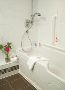 惠特彻奇麦克唐纳德山谷高尔夫Spa酒店的带淋浴和毛巾浴缸的浴室