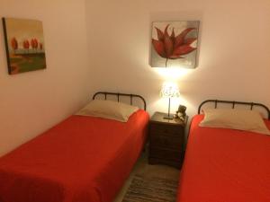 Episkopi PafouPiskopos Country House的宿舍间内的两张床,配有红色床单和一盏灯