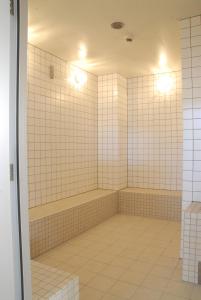 白河市棚仓町文艺复兴旅馆的浴室配有白色瓷砖墙壁和浴缸。