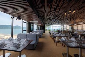 岘港Belle Maison Parosand Da Nang Hotel -managed by H&K Hospitality的一间设有桌椅的海景餐厅