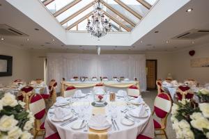 拉格比金狮酒店的宴会厅配有白色的桌椅和吊灯。