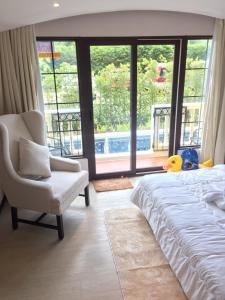 乔木提恩海滩Venetian Signature PoolAccess Resort Jomtian Pattaya的卧室配有床、椅子和大窗户