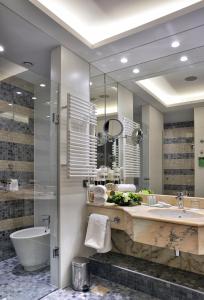 布拉格Hotel Savoy Prague的一间带大镜子、浴缸和水槽的浴室