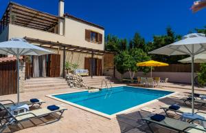 阿斯特里昂Amazing Villas in Crete的房屋旁的游泳池配有椅子和遮阳伞