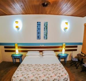 圣塞巴斯蒂昂-杜帕拉伊苏Pousada Nascentes da Fortaleza, antiga Água Azul的一间卧室配有一张带两张桌子和两盏灯的床。