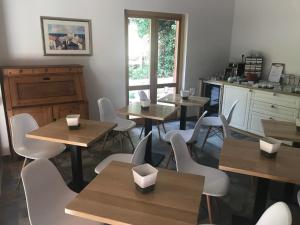 波尔托罗Wingbay B&B的配有木桌和白色椅子的餐厅