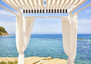 卡斯特拉巴特阿普罗多海水浴Spa度假酒店的白色的凉亭,背靠大海