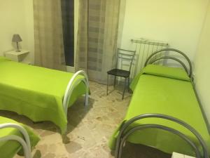 莫诺波利Domenico s holiday houses的一间设有两张绿色的床和椅子的房间