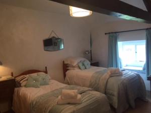 AskhamWhite Cottage Askham的一间卧室设有两张床,墙上配有电视。